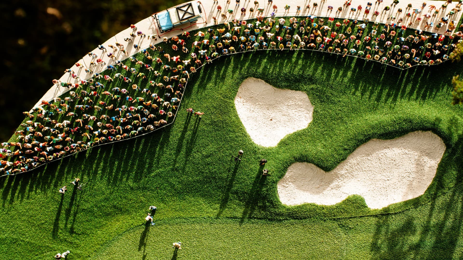 Aerial view of a miniature landscape of the spectators surrounding the championship green in a handcrafted golf course model